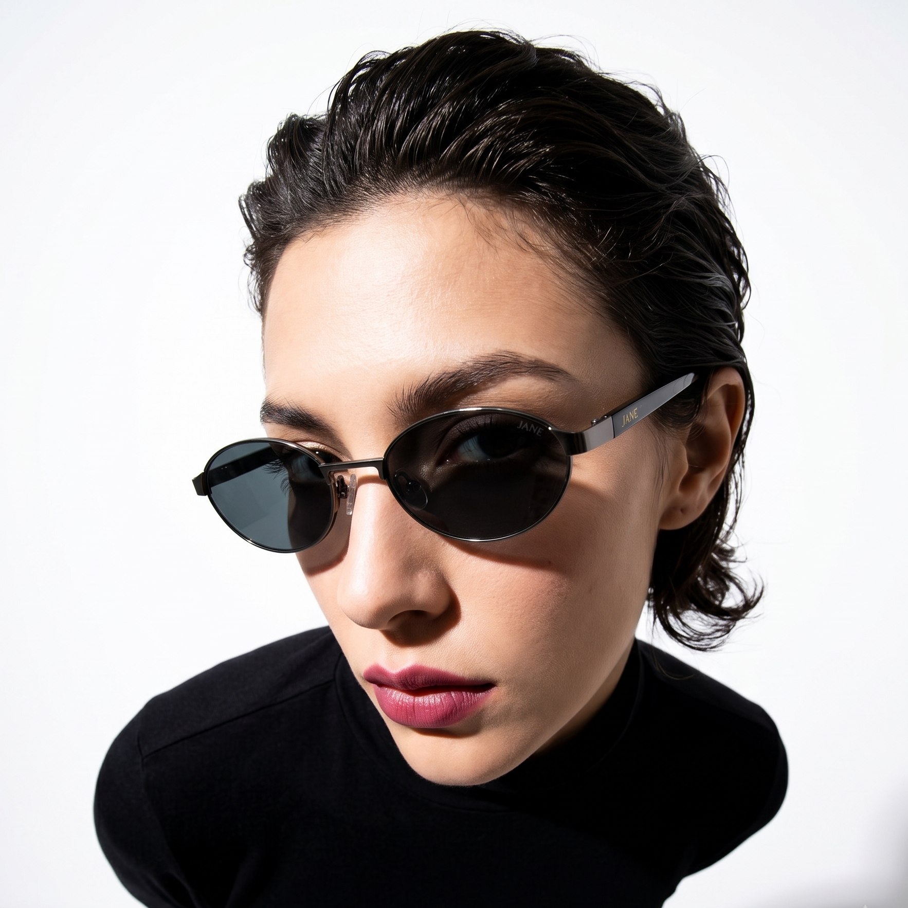Woman wearing black sunglasses and a black outfit against a white background